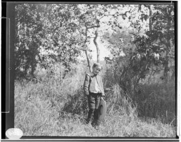 A young boy holding his hat