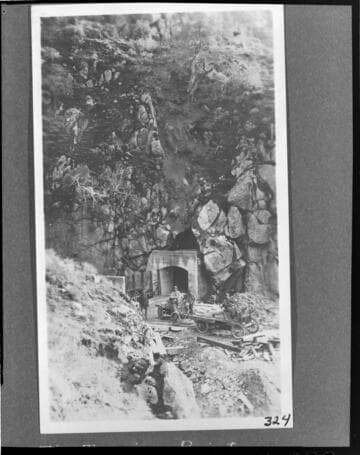 Men in their automobiles near mouth of tunnel