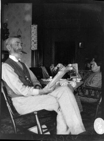 A couple sitting around a tea table.  The elderly man