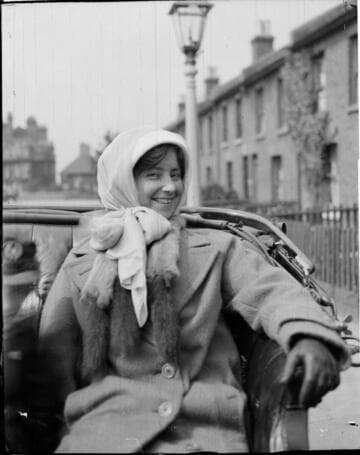 A young woman sitting in a carriage wearing a coat