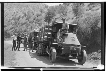 Men standing by a line of Mack Bulldog trucks