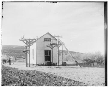 An exterior view of Exeter Substation #2 showing transmission lines and a farm or ranch in the background