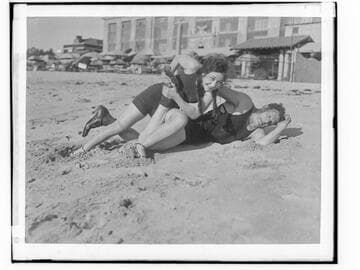 Henry Steinborn and a woman posed like wrestlers on the beach in front of Club Casa del Mar