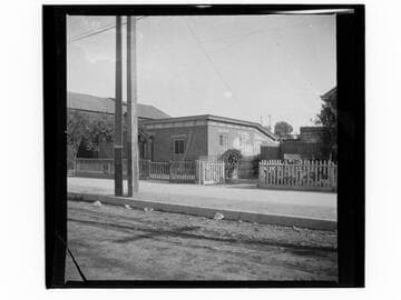 Unidentified street with sidewalk, fence and small brick building