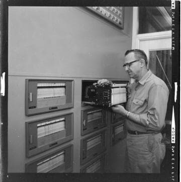 Worker inspecting data recorders in control room and over view of generation deck at Alamitos Generating Station