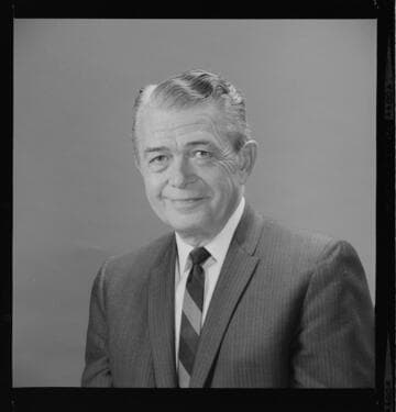 Execs. reviewing photographs at desk, and off-set portraits of both men