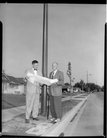 Two men by residential streetlight looking at plans