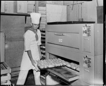 Chef taking tray of baked potatos out of a baking oven